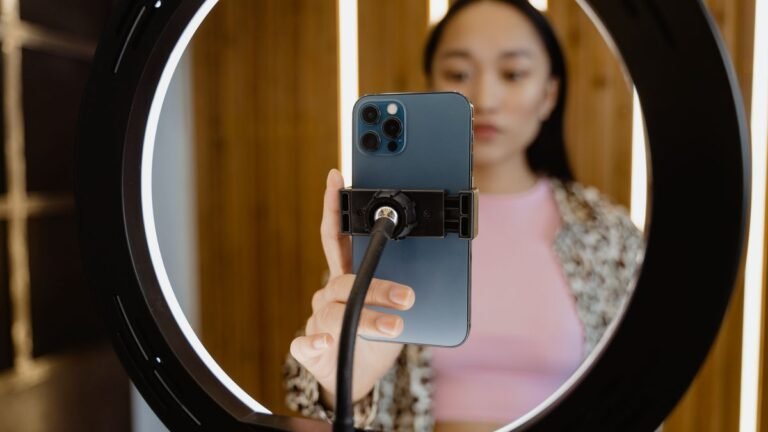 Jovem gravando um vídeo com o celular fixado em um ring light dentro de casa